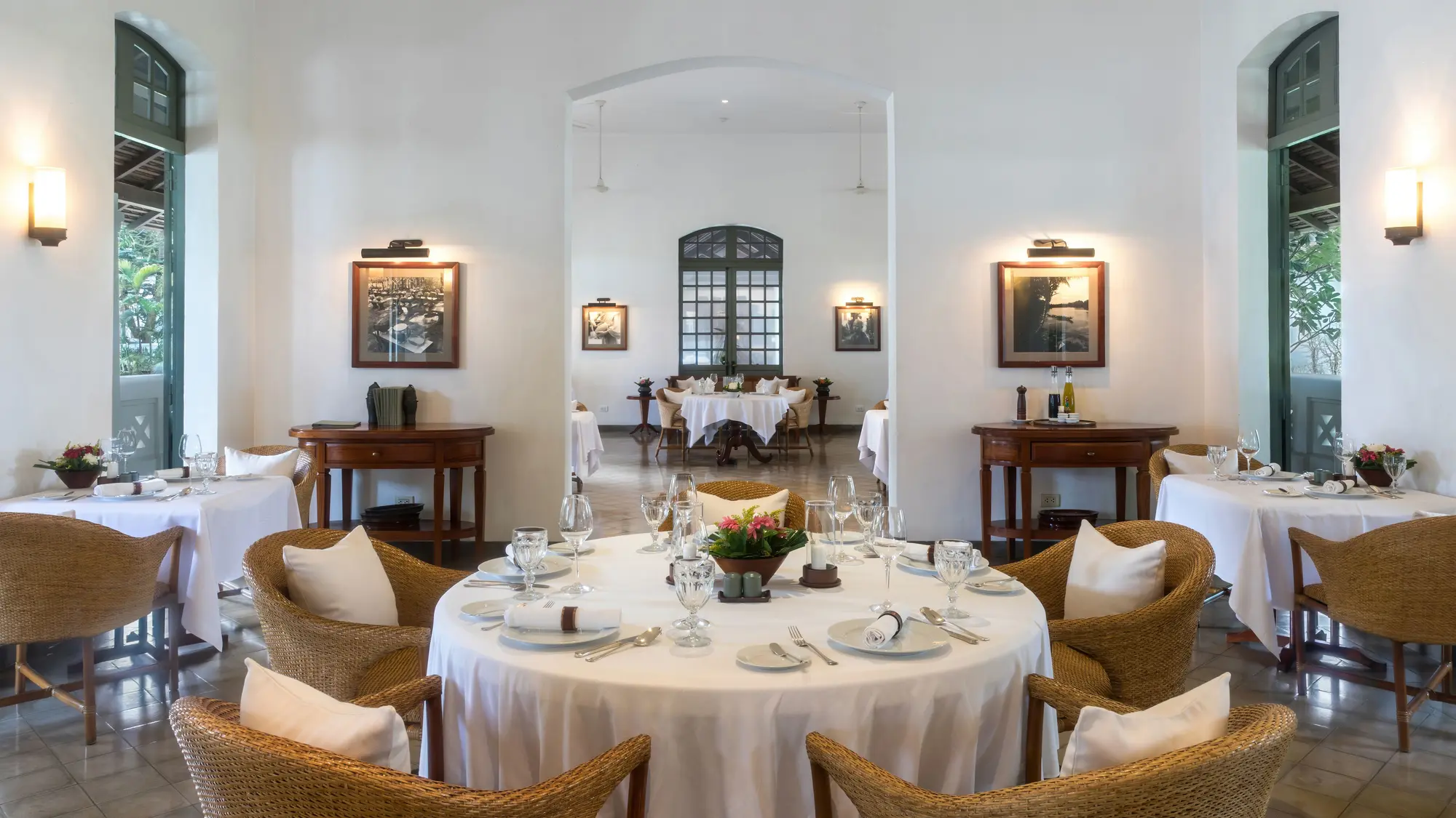 A hotel restaurant dining room with round tables laid with white linen, glassware and cutlery, ready for service